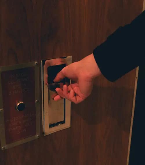 A hand swiping an access card into a security panel.