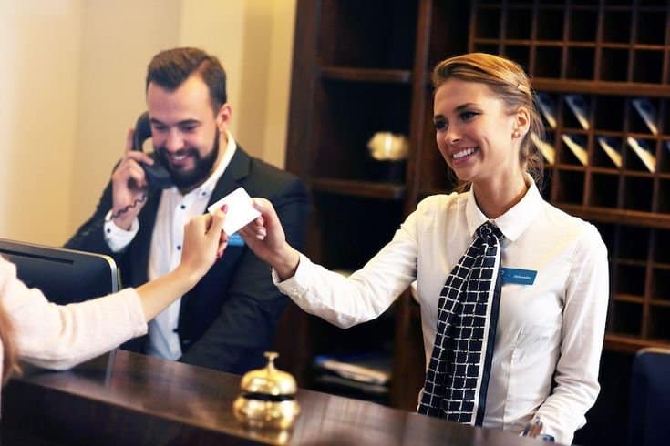 Female security receptionist on phone at a corporate reception desk.