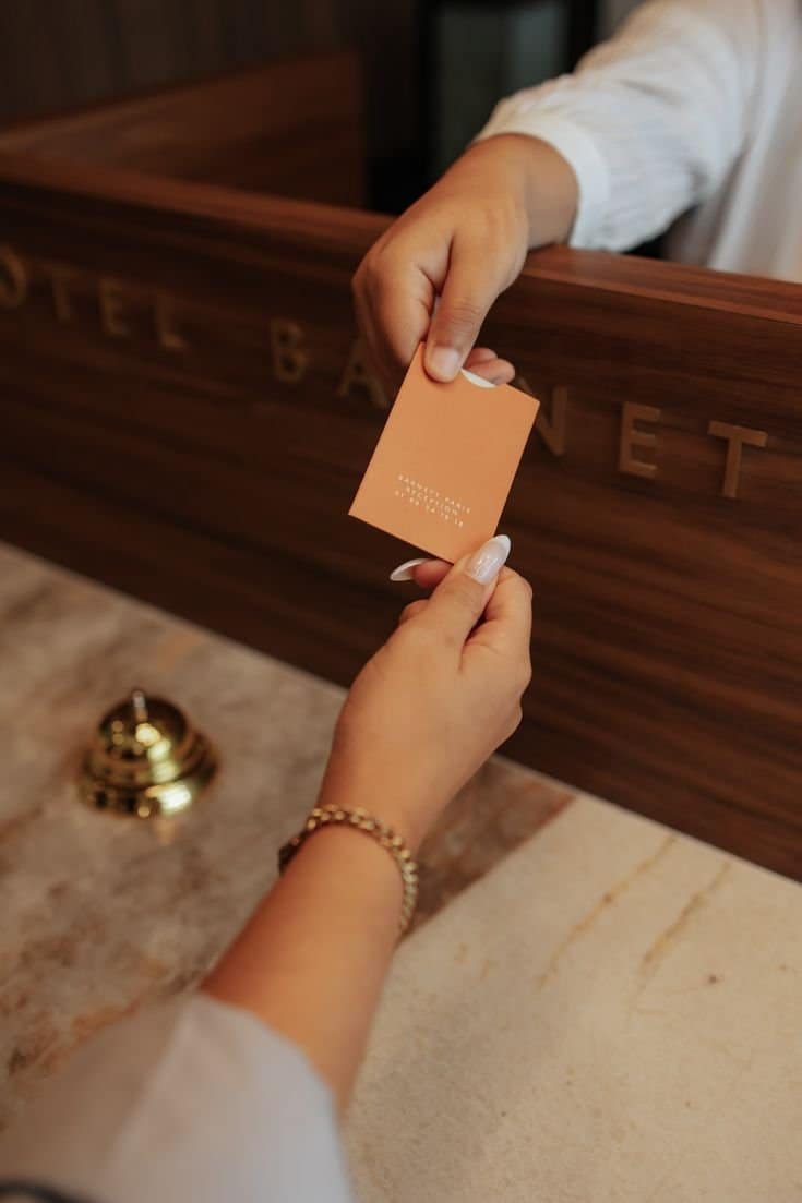 A person handing a key card to a receptionist at a front desk.